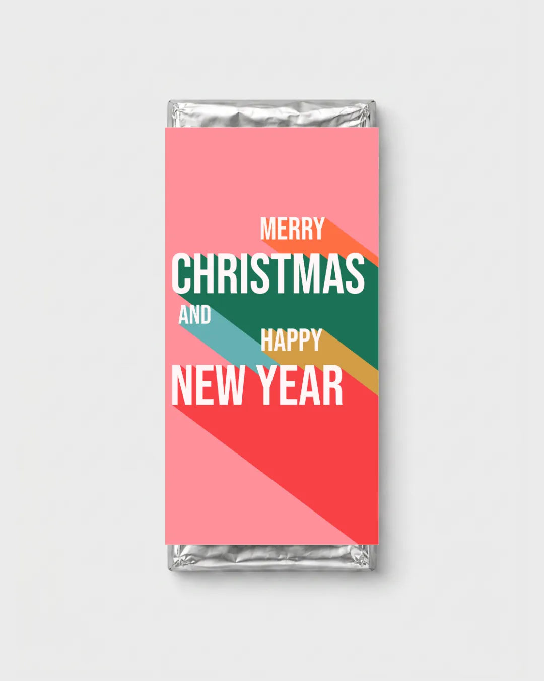A wrapped chocolate bar with a festive New Year's Eve label. The label features a pink background with diagonal color blocks of orange, teal, green, and red, overlaid with white text reading 'MERRY CHRISTMAS AND HAPPY NEW YEAR'.